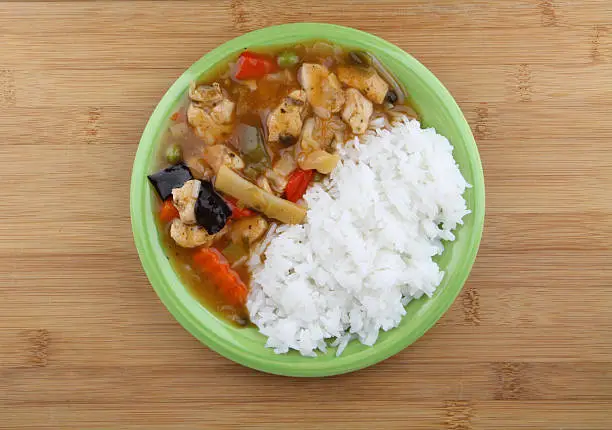 Rice with chicken and vegetable on green plate.