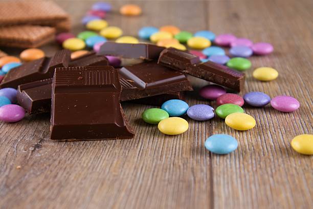 pralina di cioccolato con colore smarties su tavola di legno - biscuit red blue macro foto e immagini stock