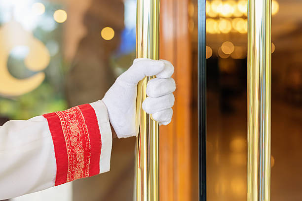 Concierge Opens the Door at Luxury Hotel Entrance Hand of Concierge, Doorman dressed in typical clothes and white gloves opens the door and welcomes the guest at the entrance of a luxury hotel. Agra, India. door attendant photos stock pictures, royalty-free photos & images