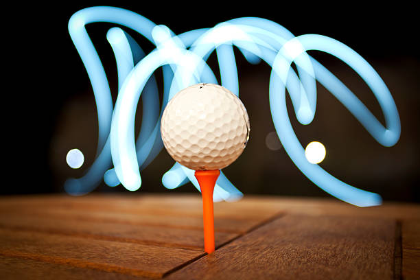 Golf Ball on a tee with streaks of light behind Golf Ball on a tee with streaks of light behind night golf stock pictures, royalty-free photos & images