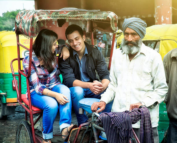 Young indian couple in rickshaw w their driver. A young modern indian couple going home in a rickshaw old delhi stock pictures, royalty-free photos & images