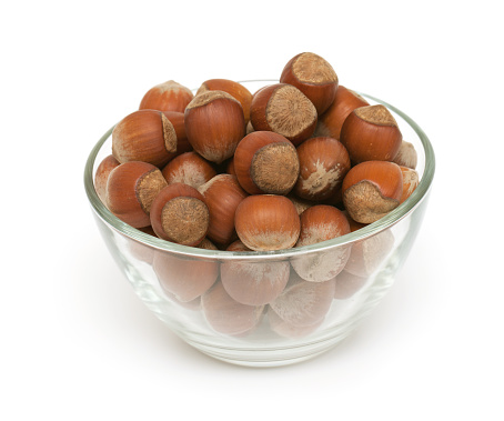 hazelnuts in a bowl over white
