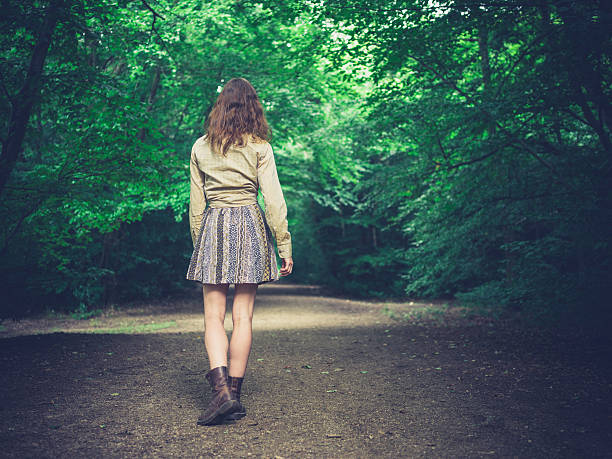 istock Young woman walking on road in forest 485923206