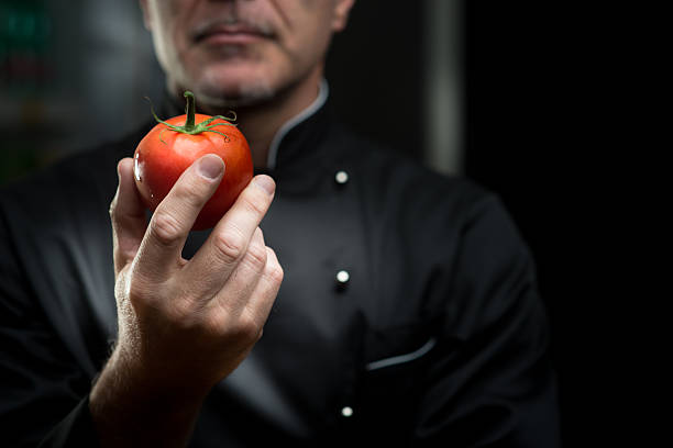 chef con un pomodoro - professional chef foto e immagini stock