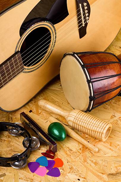 Set of various music instruments on OSB board Vertical photo with set of musical instruments on wooden OSB board as green egg shaker, guiro, bongo drum, few guitar picks, harmonica and acoustic guitar. guiro stock pictures, royalty-free photos & images