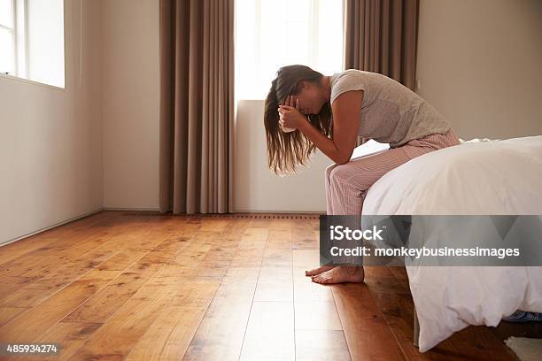 Woman Suffering From Depression Sitting On Bed And Crying Stock Photo - Download Image Now