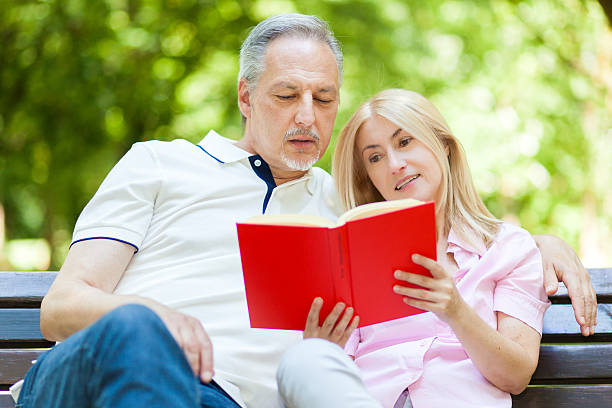 istock Couple reading a book in the park 485934496
