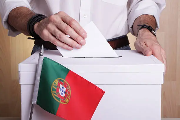 A citizen casting his vote. Portuguese flag in front of the ballot box