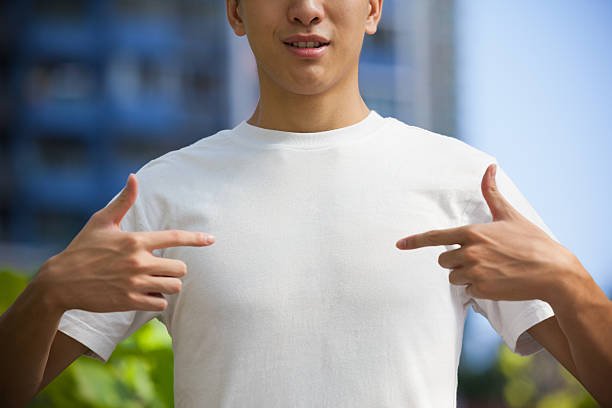 uomo che indica al suo vuoto t-shirt bianca - plain shirt foto e immagini stock