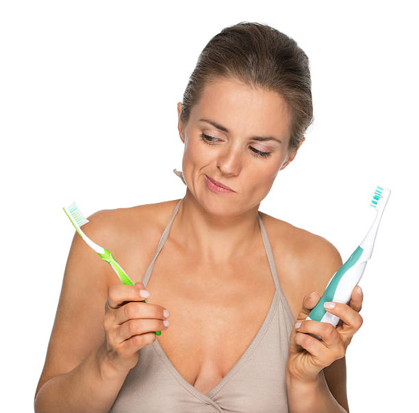 istock Doubting woman choosing between old and electric toothbrush 485946051
