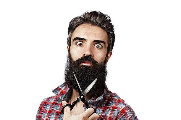 Wide-eyed man with crazy look and long beard holding scissors
