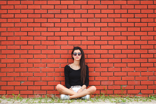 Woman look at camera with brick wall.