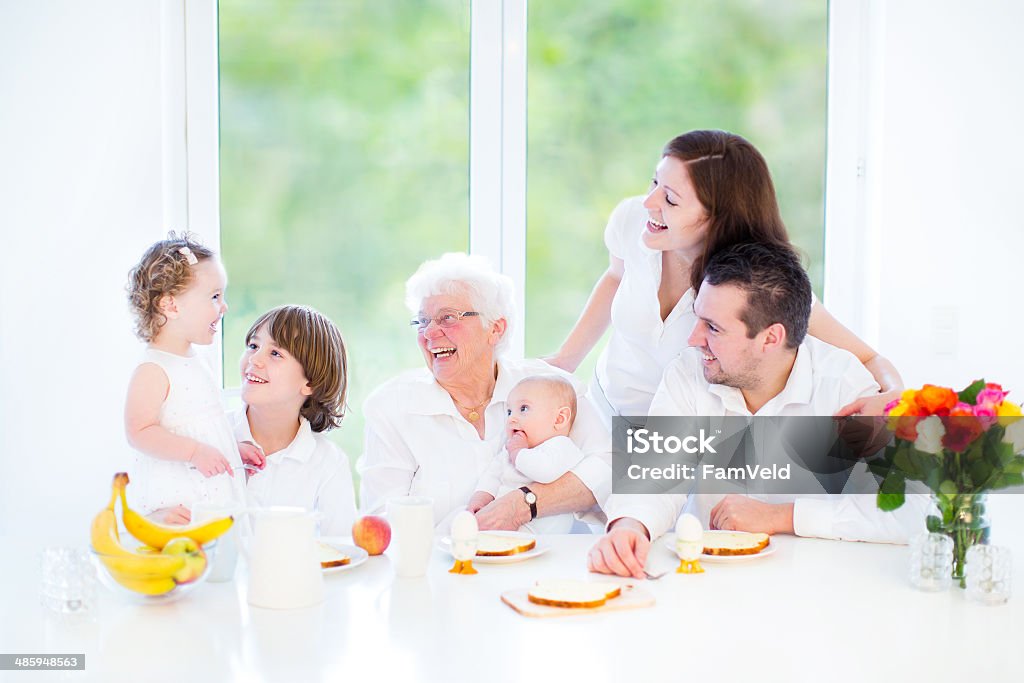 Happy young family having fun at breakfast with their grandmother Active Seniors Stock Photo
