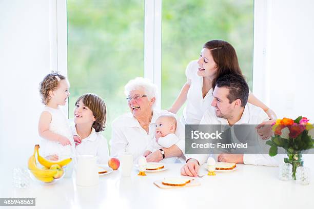 Happy Young Family Having Fun At Breakfast With Their Grandmother Stock Photo - Download Image Now