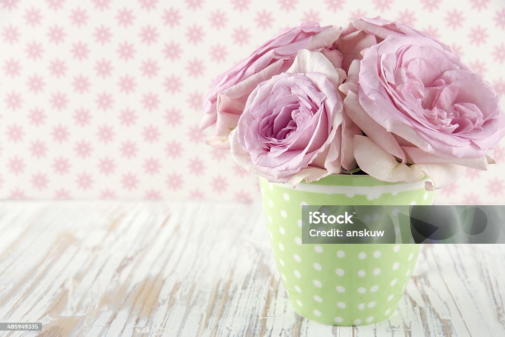 Roses in a green polkadot vase on vintage Pink roses in a green polkadot vase on vintage white wooden shabby chic background Antique Stock Photo