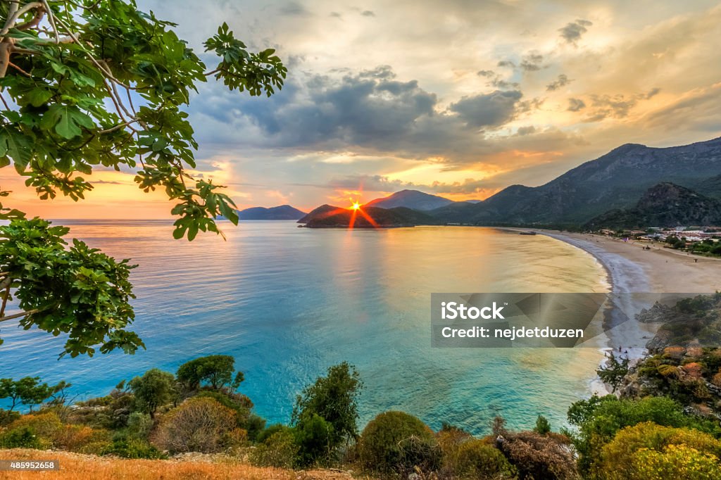 Oludeniz Sunset Oludeniz remains one of the most photographed beaches on the Mediterranean. It has a secluded sandy bay at the mouth of Ölüdeniz, on a blue lagoon, The beach itself is a pebble beach. The lagoon is a national nature reserve and construction is strictly prohibited. The seawater of Oludeniz is famous for its shades of turquoise and aquamarine,  2015 Stock Photo