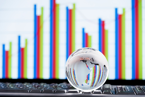 Glass globe on computer keyboard with the background of business chart.