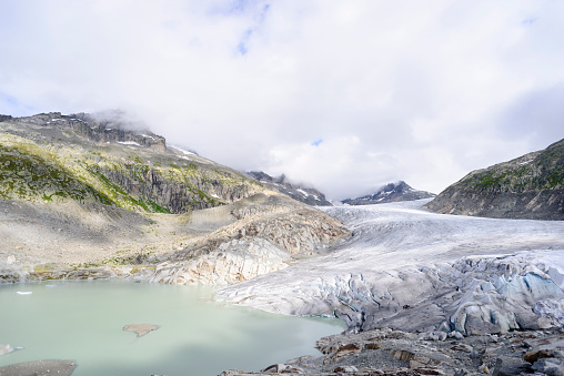 The foot of the Rhone glacier in the Swiss Alps, in summer. The glacier, source of the Rhone, is currently (in 2015) receding at a rate of seven metres per year due to global warming. People standing on the glacier give an idea of scale.
