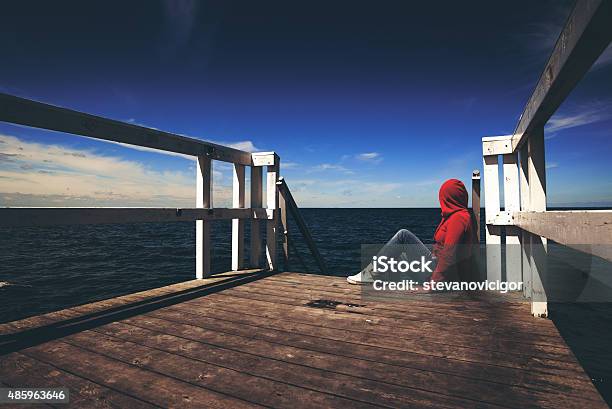 Alone Woman In Red Shirt At The Edge Of Pier Stock Photo - Download Image Now - Hooded Shirt, One Woman Only, Women