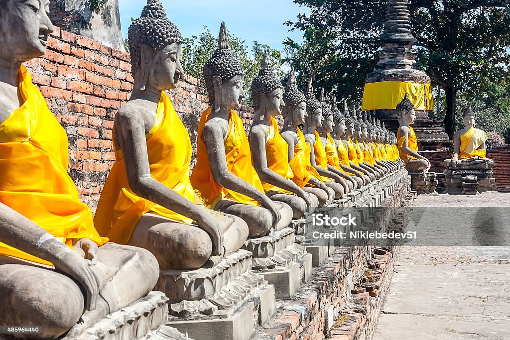 The prospect of a number of statues of Buddha, Thailand. The prospect of a number of statues of seated Buddha, Thailand. Statues in yellow festive decoration. Bright sunny day. 2015 Stock Photo