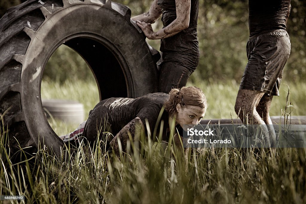 group of friends doing tyre obstacle during mud run Healthy Lifestyle Stock Photo