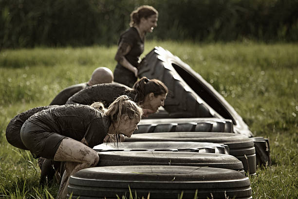 grupo de amigos captar pneus durante a corrida na lama - mud run imagens e fotografias de stock