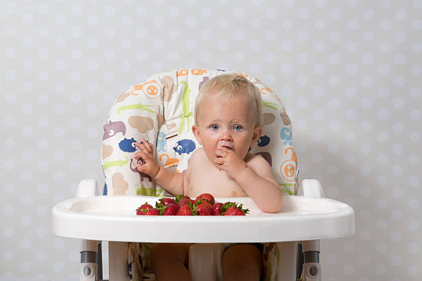 Baby girl eating strawberries stock photo