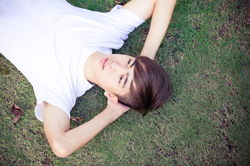 Young Chinese Teenager Lying on Grass Field.