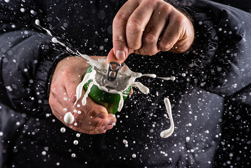 Man opening a beer tin and frothy foam splashing out