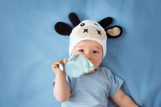 ребенок в воловью кожу шляпа пьет молоко - milk bottle стоковые фото и изображения
