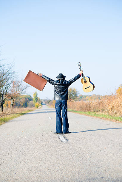istock Man holding hands up with suitcase and guitar 485973734