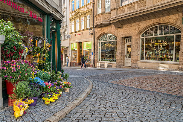 Jena, Germany - April 17, 2014: Historic center of Jena, Germany with old shops for alcohol and vine and a beautiful flower shop. This street calls Saalstrasse. People walking in the street. 