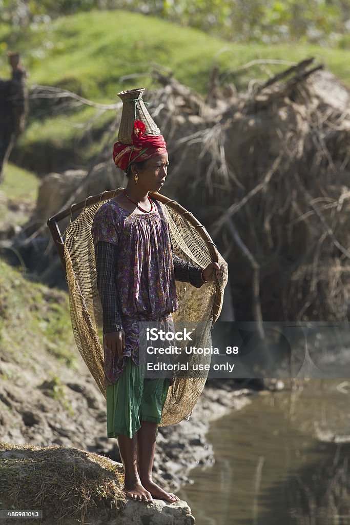 Nepali Taru woman wearing traditional fishing clothe Bardia Nepal - November 11, 2013: Nepali Taru woman wear traditionnal hat and nest use for river fishing. Adult Stock Photo