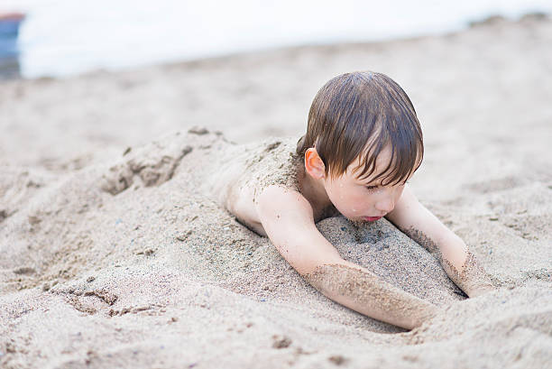 istock Boy Buried in Sand at a Beach in Summer 485981092
