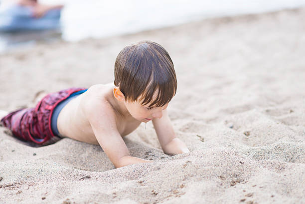 istock Wet Boy Laying in Sand Starting to Dig at Beach 485981148