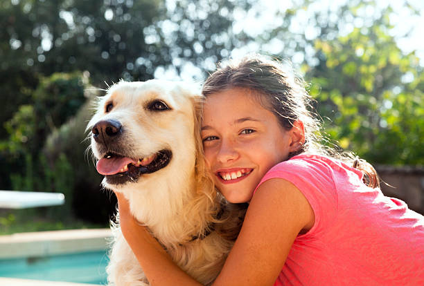 Eleven years old girl hugging her golden retriever dog, outdoors.
