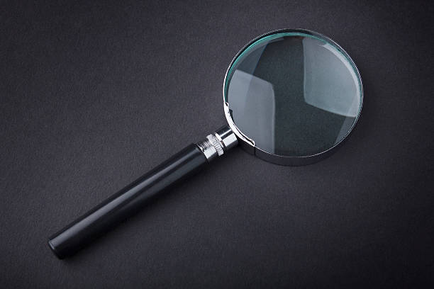 istock Closeup of magnifying glass on dark surface 485985173