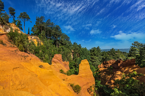Green trees create contrast with the ocher. Multi-colored ocher outcrops - from yellow to orange-red. Roussillon, Provence Red Village