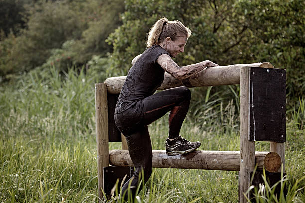 istock woman climbing over wooden obstacle during mud run 485995226