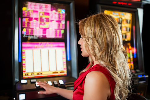 Woman Playing On Slot Machines At The Casino Stock Photo - Download Image Now - One Woman Only, Only Women, Women - iStock
