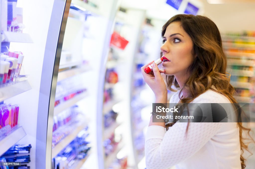 Perfect lipstick color Beautiful woman applying perfect lipstick color in shopping mall Make-Up Stock Photo