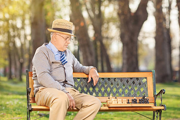 Lonley senior playing chess in park