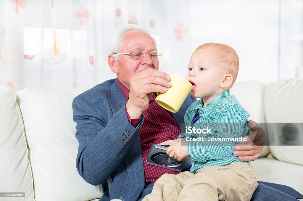 Nonno offre il suo nipote una tazza di latte - Foto stock royalty-free di 70-79 anni