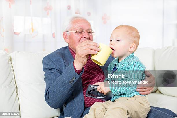 Nonno Offre Il Suo Nipote Una Tazza Di Latte - Fotografie stock e altre immagini di 70-79 anni - 70-79 anni, Abbigliamento casual, Abbigliamento da neonato