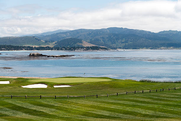 Golf at Pebble Beach Monterey, California, USA - May 15, 2015: View at the green at the 18th hole at Pebble Beach Golf Course along side the Pacific Ocean, during a summer day. Pebble Beach Golf Course is one of the nations most well known. pacific grove stock pictures, royalty-free photos & images