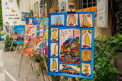 Marseille, France - August 13, 2015: A painter (not pictured) sells some colorful paintings on the street in the historic district of Le Panier. The paintings portray the views of Marseille and boats.