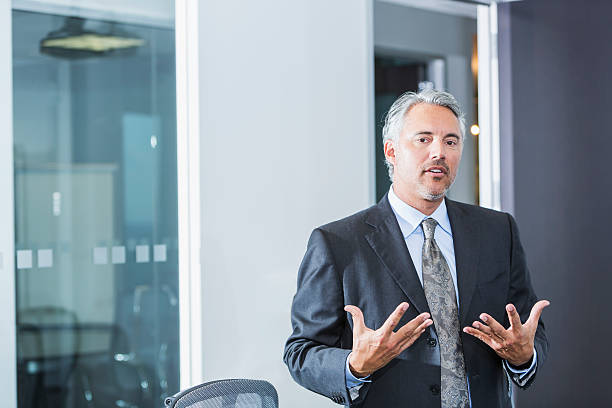 empresário vestindo cinza terno em pé no escritório - one person businessman board room business person - fotografias e filmes do acervo