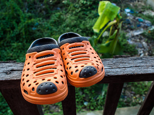 istock Pair of orange rubber slippers on old wooden 486018100