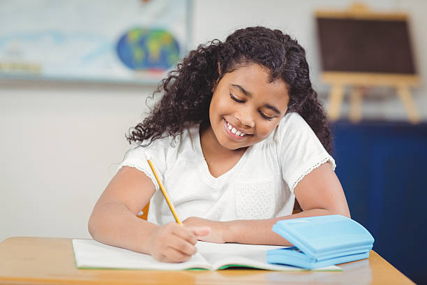istock Cute pupil working at her desk in a classroom 486021946