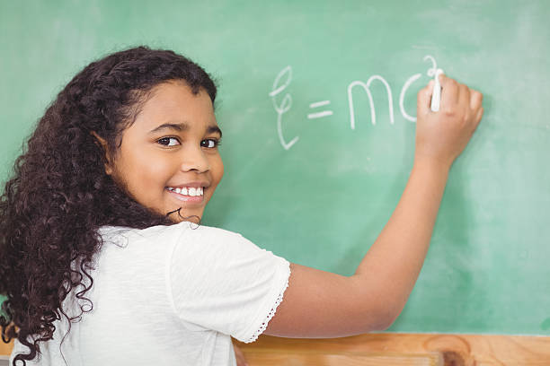 istock Smiling pupil writing on chalkboard in a classroom 486021982